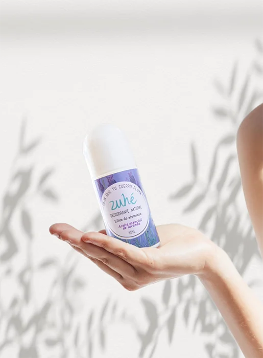Mujer feliz mostrando un desodorante natural Zühe en un entorno fresco